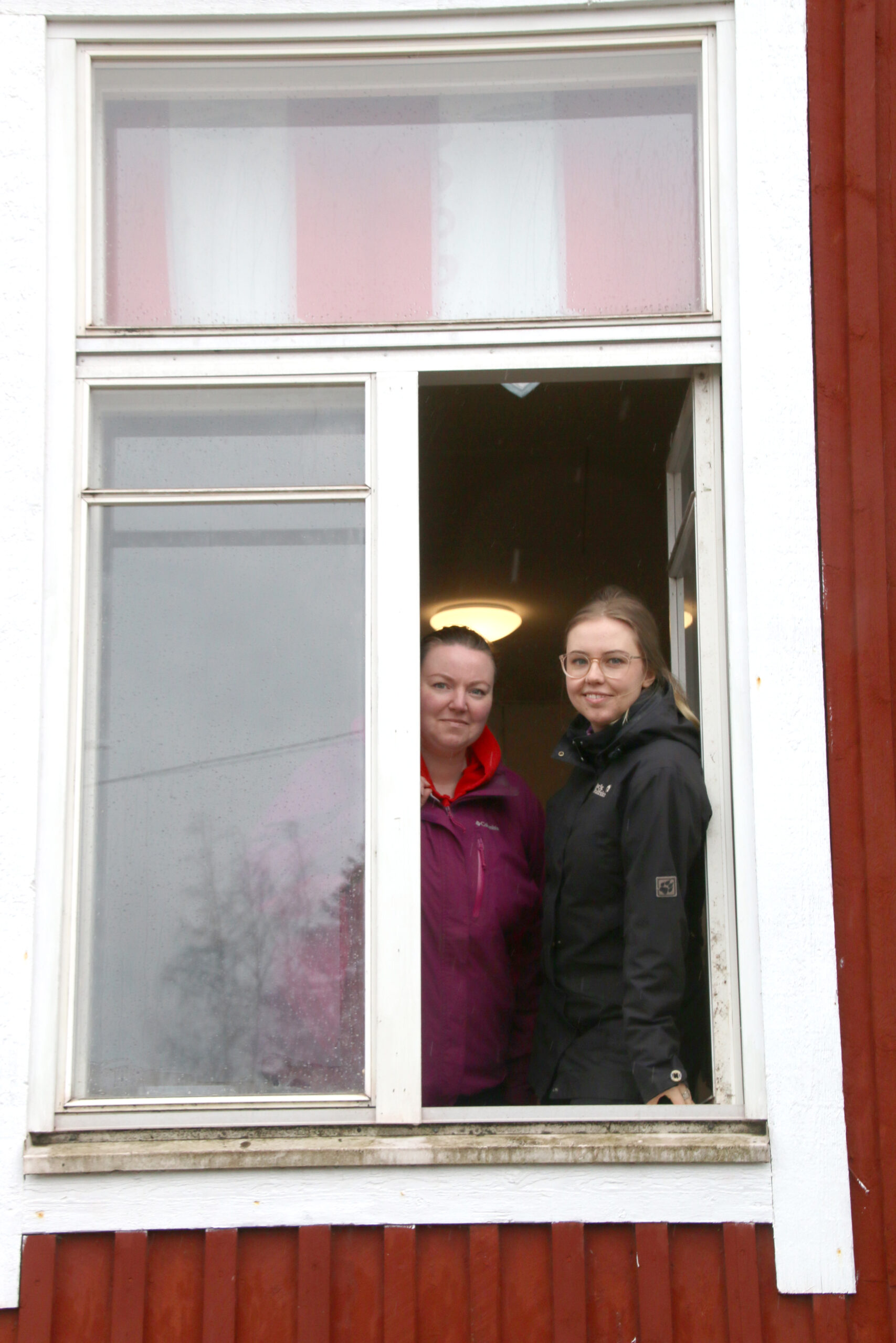 Kaksi naista katsoo nuorisoseuran ikkunasta ulos.